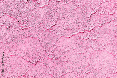 Rough old painted pink wall background with cracks and scratches. Aged and weathered coating of concrete or metal surface.