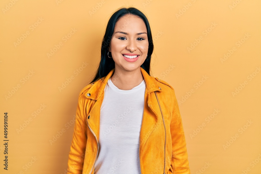 Beautiful hispanic woman with nose piercing wearing yellow leather jacket with a happy and cool smile on face. lucky person.