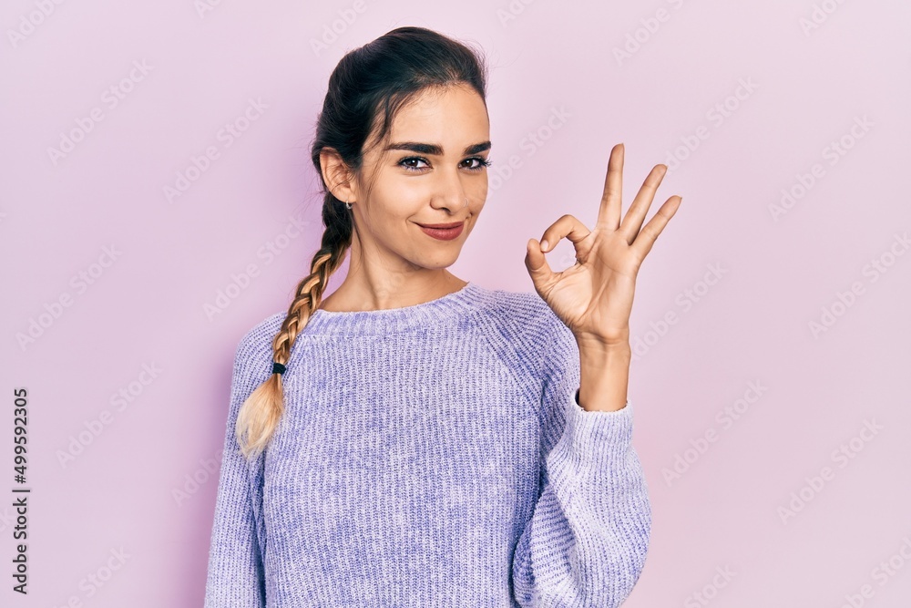 Young hispanic girl wearing casual clothes smiling positive doing ok sign with hand and fingers. successful expression. Young hispanic girl wearing casual clothes smiling positive doing ok sign with hand and fingers. successful expression.