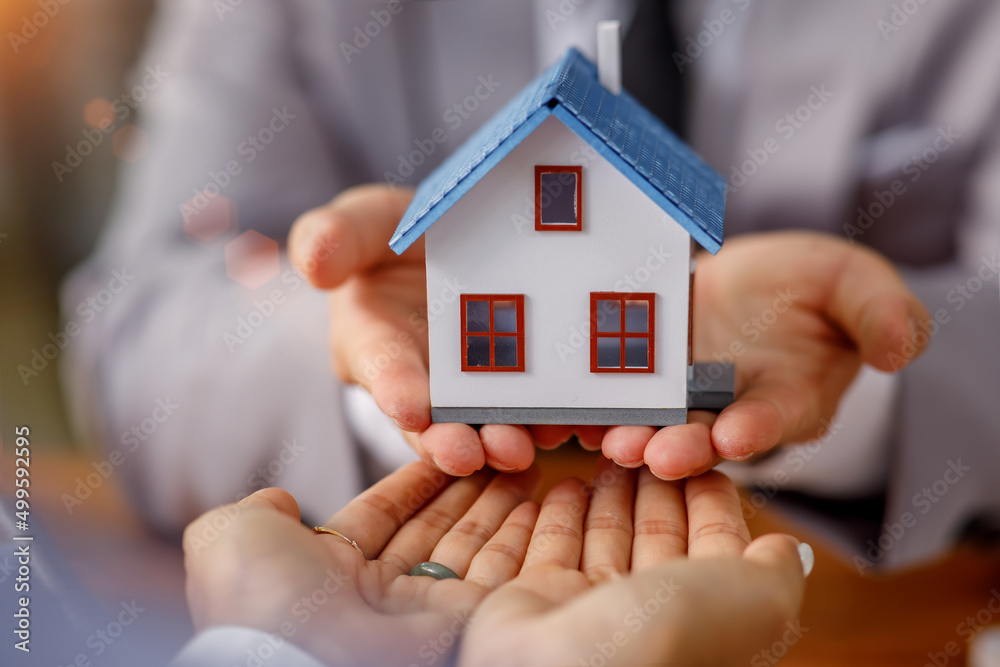 Real estate brokerage agent Deliver a sample of a model house to the customer, mortgage loan agreement Making lease and buying a house And contract home insurance concept Real estate brokerage agent Deliver a sample of a model house to the customer, mortgage loan agreement Making lease and buying a house And contract home insurance concept