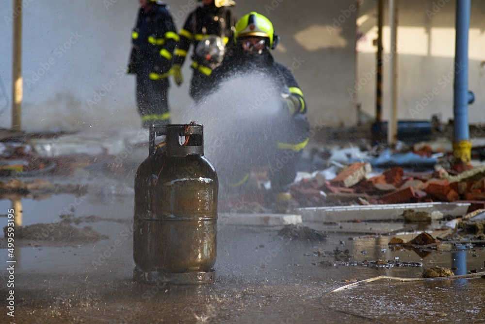 Firefighter with breathing apparatus uses a stream of water to cool a