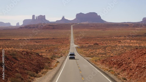Aerial view of a RV on a road with Monument Valley peaks in the background - tracking, drone shot photo