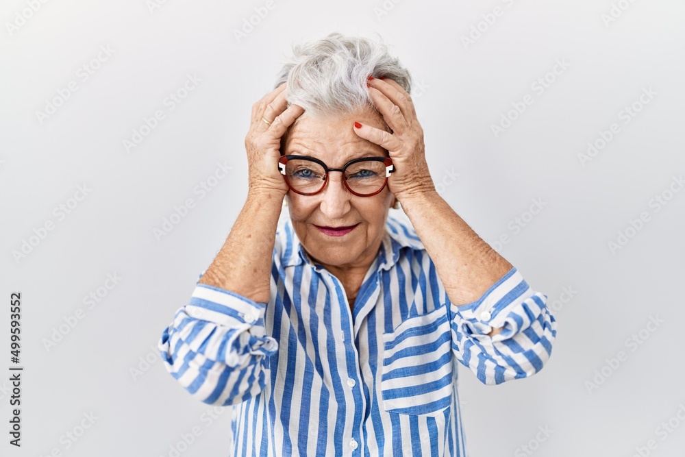 Senior woman with grey hair standing over white background suffering from headache desperate and stressed because pain and migraine. hands on head. Senior woman with grey hair standing over white background suffering from headache desperate and stressed because pain and migraine. hands on head.