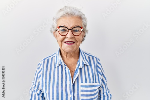 Murais de parede Senior woman with grey hair standing over white background with a happy and cool smile on face