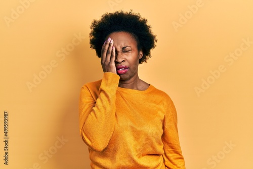 Young african american woman wearing casual clothes yawning tired covering half face, eye and mouth with hand. face hurts in pain. © Krakenimages.com