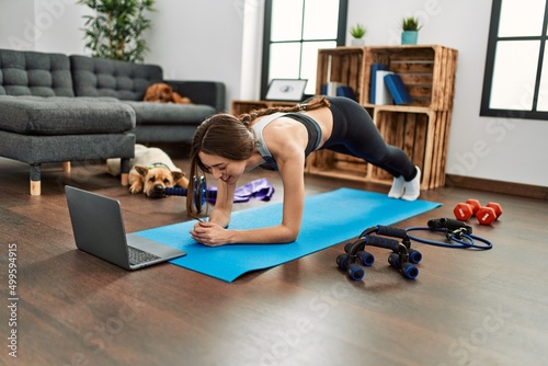 Young hispanic woman smiling confident having online abs exercise class at home