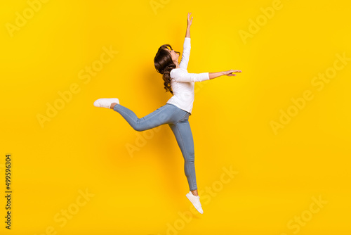 Foto Photo of adorable shiny woman wear white shirt jumping high dancing isolated yel