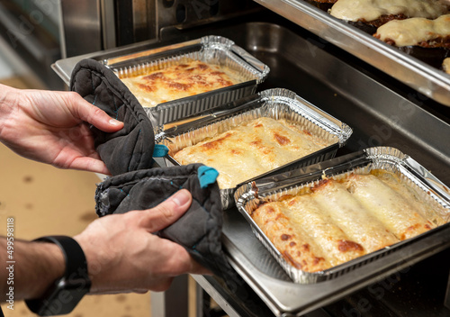 Tableau sur toile the hands of an unrecognizable cook taking cannelloni out of the oven