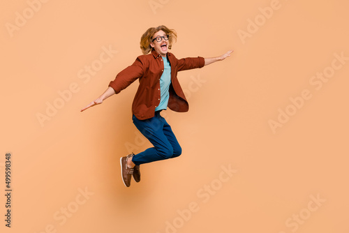Full length body size view of attractive cheerful crazy guy jumping fooling having fun isolated over beige pastel color background