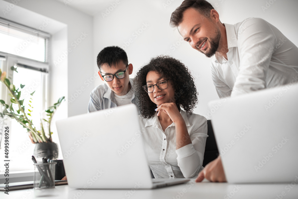 Cheerful diverse colleagues working on laptop Cheerful diverse colleagues working on laptop