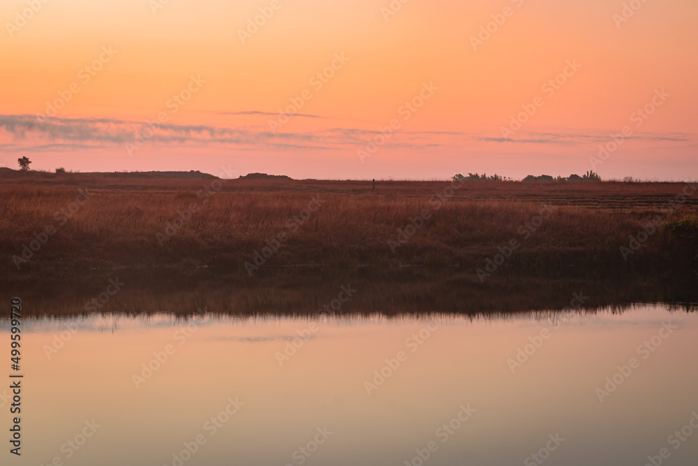 calm lake with dramatic sunrise orange sky reflection at morning