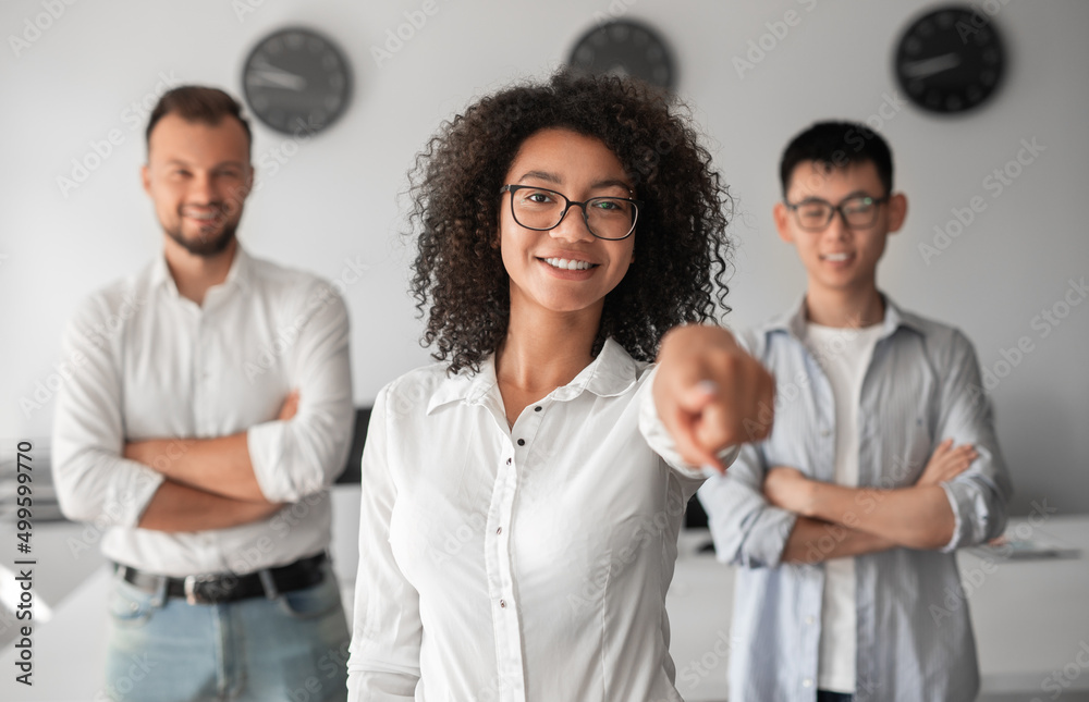 African American female manager pointing at camera near coworkers in office African American female manager pointing at camera near coworkers in office