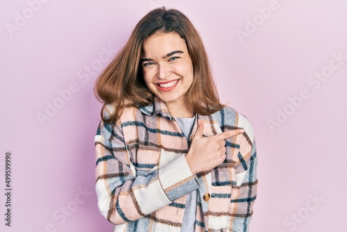 Young caucasian girl wearing casual clothes cheerful with a smile on face pointing with hand and finger up to the side with happy and natural expression © Krakenimages.com