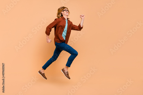 Full length body size view of attractive cheerful anergetic guy jumping running bargain isolated over beige pastel color background