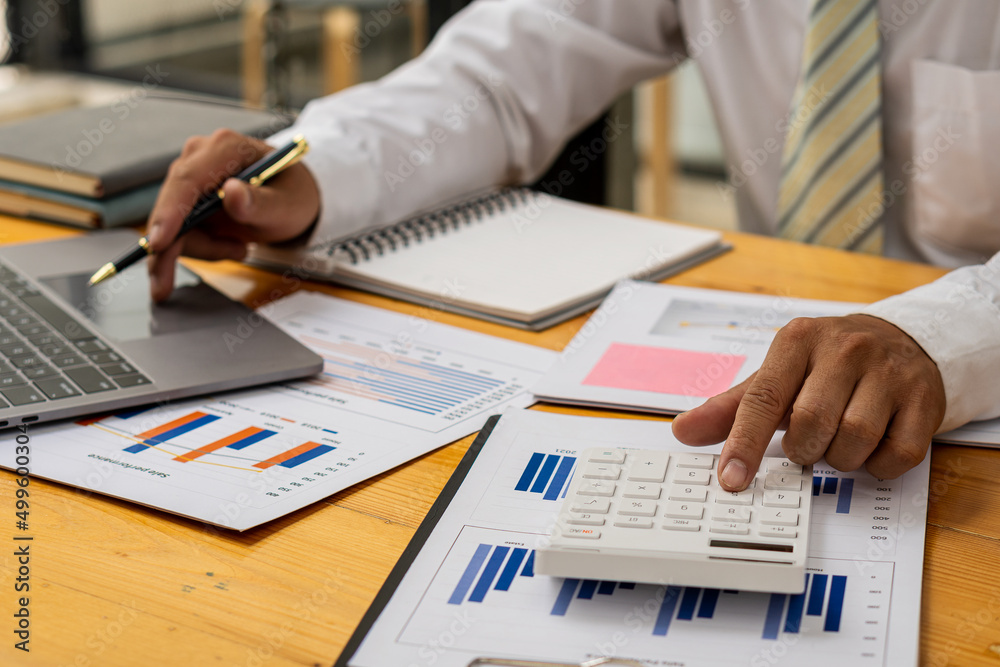 Businessman's hands pressing a calculator, calculating, analyzing, graphing, charting, accounting worker working on a laptop. A bank clerk who advises making financial reports or company profits. Businessman's hands pressing a calculator, calculating, analyzing, graphing, charting, accounting worker working on a laptop. A bank clerk who advises making financial reports or company profits.