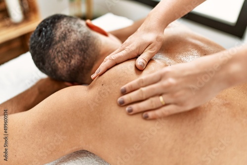 Young hispanic man having back massage at beauty center