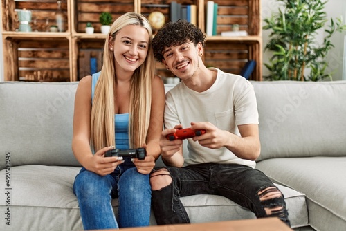 Young couple smiling happy playing video game at home.