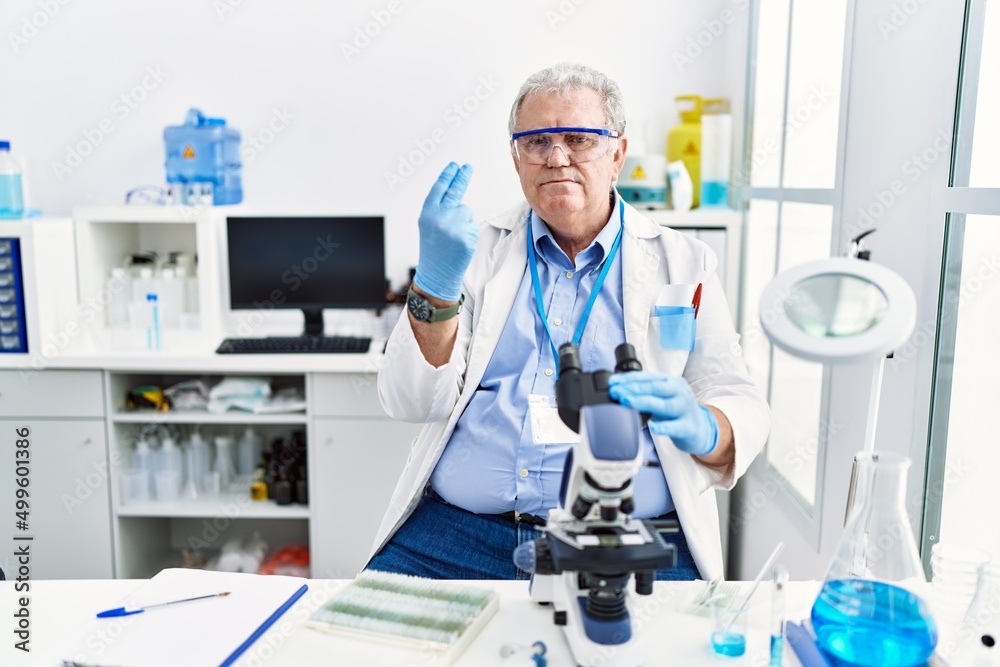 Senior caucasian man working at scientist laboratory doing italian gesture with hand and fingers confident expression