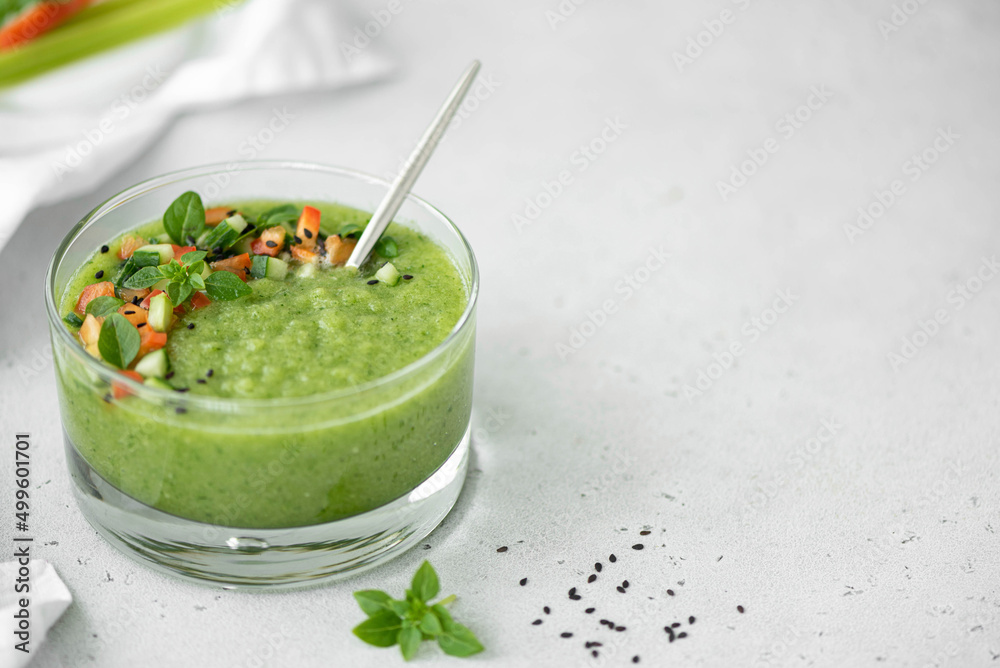 chilled cucumber gazpacho with tomato pieces and basil in a glass bowl, copy space chilled cucumber gazpacho with tomato pieces and basil in a glass bowl, copy space