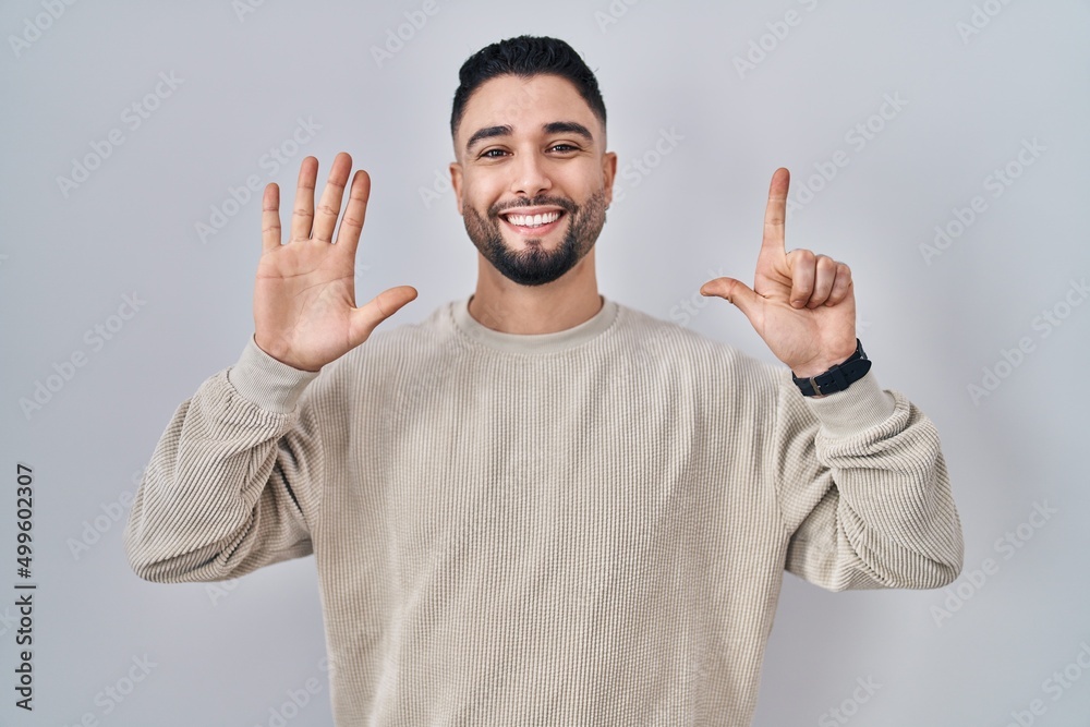 Young handsome man standing over isolated background showing and pointing up with fingers number seven while smiling confident and happy. Young handsome man standing over isolated background showing and pointing up with fingers number seven while smiling confident and happy.
