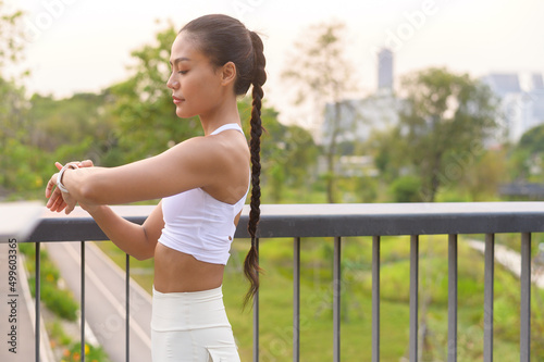 A young fitness woman in sportswear using smart watch while exercising in city park, Healthy and Lifestyles. © tonefotografia