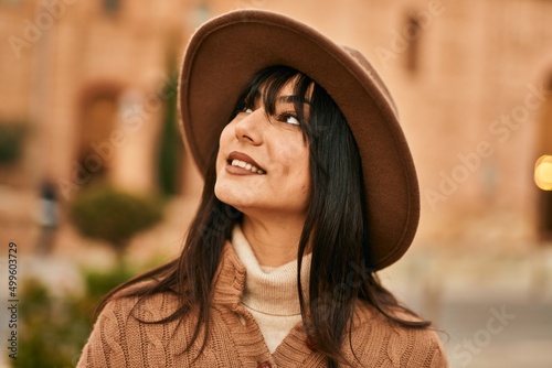 Brunette woman wearing winter hat smiling outdoors at the city © Krakenimages.com