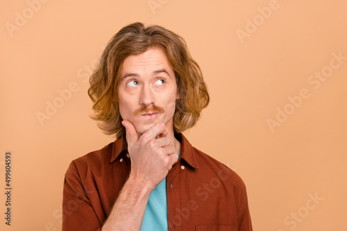 Portrait of attractive bewildered red-haired guy overthinking copy blank space isolated over beige pastel color background