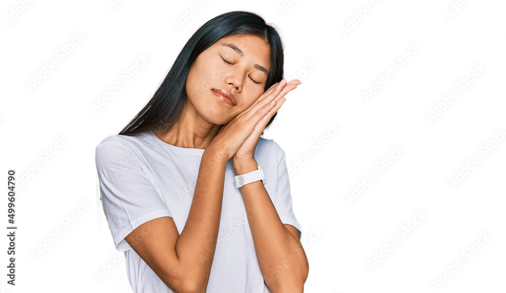 Beautiful young asian woman wearing casual white t shirt sleeping tired dreaming and posing with hands together while smiling with closed eyes. Beautiful young asian woman wearing casual white t shirt sleeping tired dreaming and posing with hands together while smiling with closed eyes.