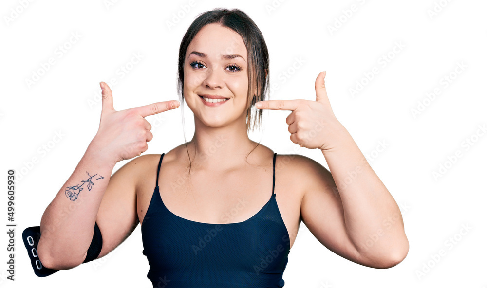 Young hispanic woman wearing sportswear smiling cheerful showing and pointing with fingers teeth and mouth. dental health concept. Young hispanic woman wearing sportswear smiling cheerful showing and pointing with fingers teeth and mouth. dental health concept.