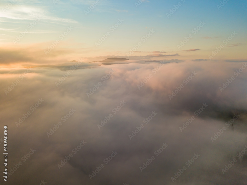 The rays of dawn over the fog in the Ukrainian Carpathians. Aerial drone view.