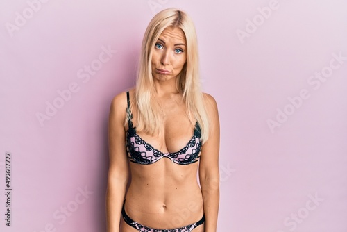 Young blonde woman wearing lingerie depressed and worry for distress, crying angry and afraid. sad expression.