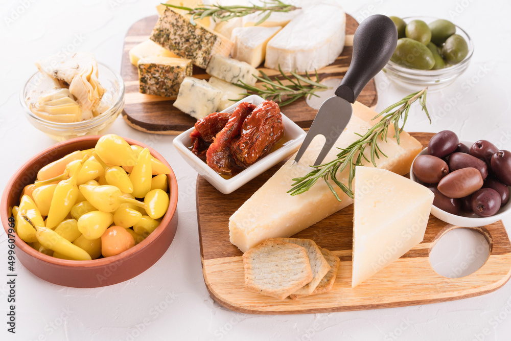 Solid and soft-ripened cheeses served with olives, pickled baby peppers, sun dried tomatoes and artichokes. Charcuterie board with cheese slices and assortment of traditional Italian antipasti