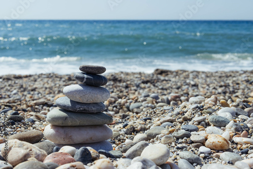 Pyramid of sea pebbles on a sunny sandy beach. The concept of life 