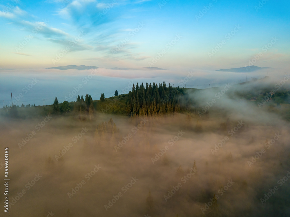Obraz premium The rays of dawn over the fog in the Ukrainian Carpathians. Aerial drone view.