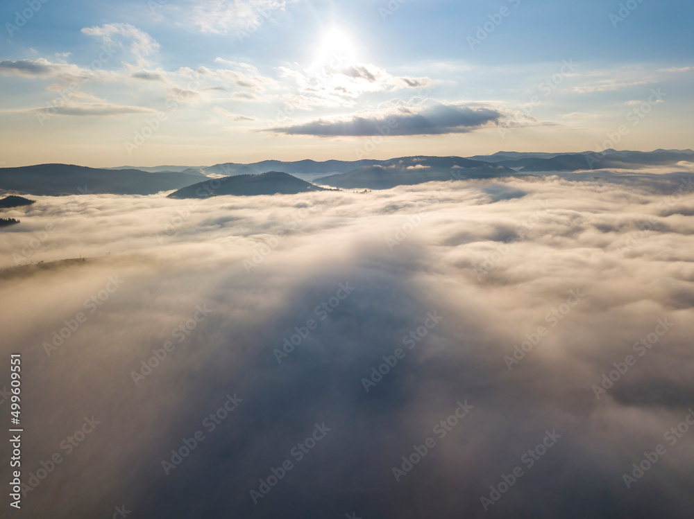 Flight over fog in Ukrainian Carpathians in summer. Mountains on the horizon. A thick layer of fog covers the mountains with a continuous carpet. Aerial drone view. Flight over fog in Ukrainian Carpathians in summer. Mountains on the horizon. A thick layer of fog covers the mountains with a continuous carpet. Aerial drone view.