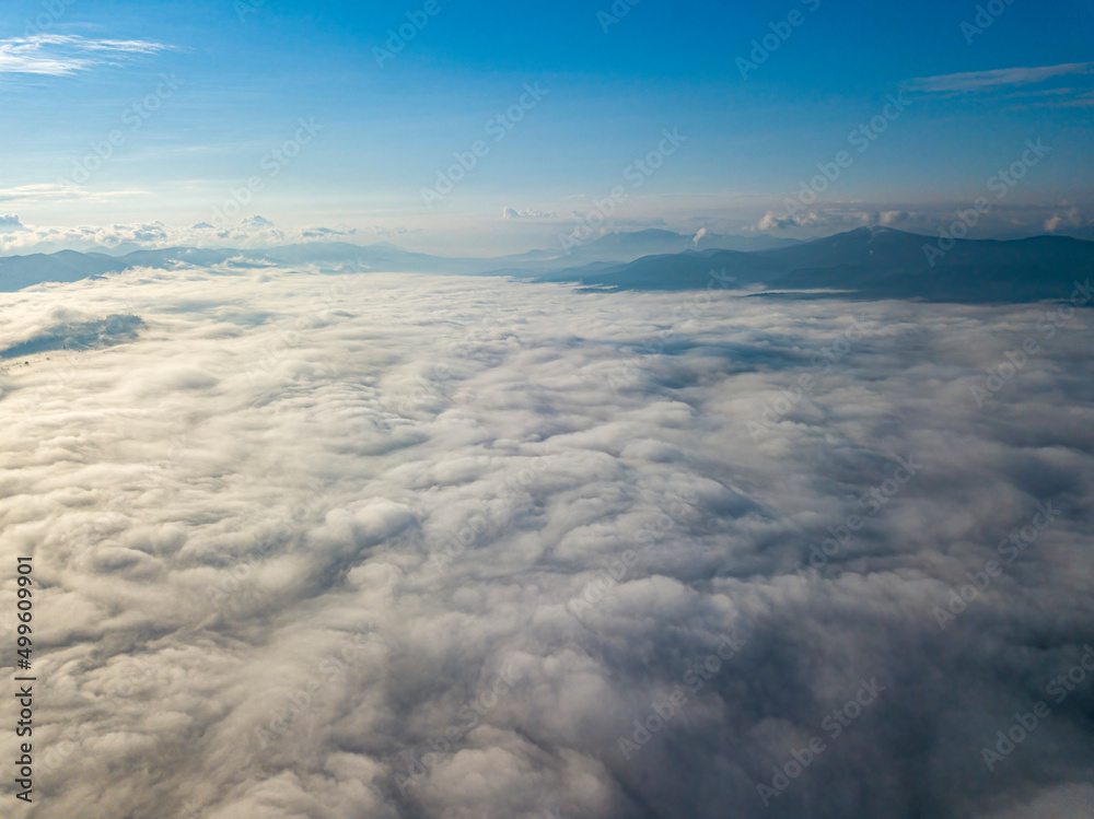 High flight above the clouds in the mountains. Aerial drone view.