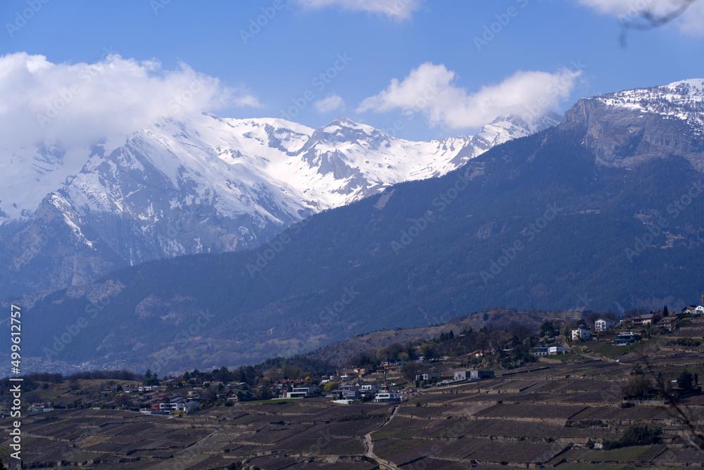 Aerial view from hill of City of Sion over the beautiful landscape of Canton Valais with the Swiss Alps on a blue cloudy spring day. Photo taken April 4th, 2022, Sion, Switzerland.