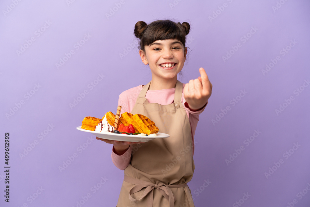 Little caucasian girl holding waffles isolated on purple background doing coming gesture Little caucasian girl holding waffles isolated on purple background doing coming gesture