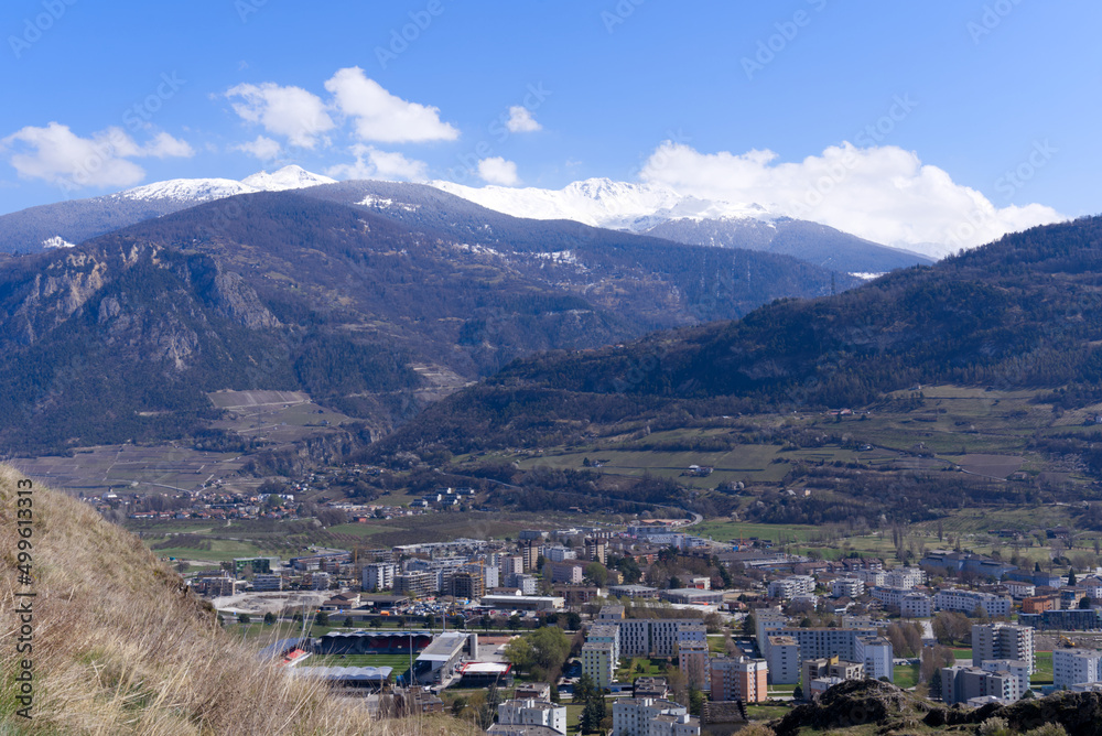 Aerial view from hill of City of Sion over the beautiful landscape of Canton Valais with the Swiss Alps on a blue cloudy spring day. Photo taken April 4th, 2022, Sion, Switzerland.