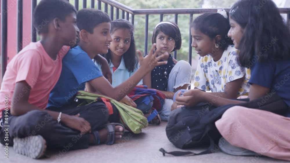 group of young school children talking with each other while sitting at school campus - concept of socializing, discussion and conversation group of young school children talking with each other while sitting at school campus - concept of socializing, discussion and conversation