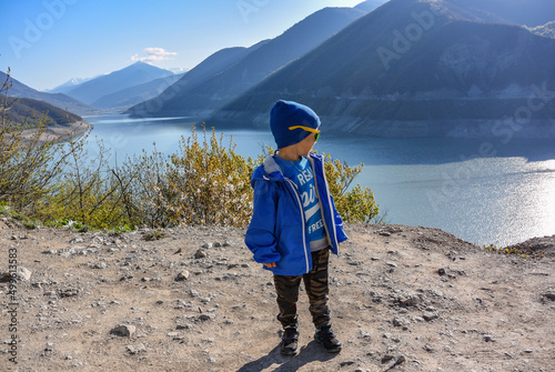 A little boy on the background of the landscape of the Zhinvali reservoir. Georgian military road. April 2019 Georgia. photo