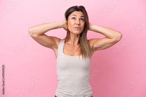 Fototapeta Naklejka Na Ścianę i Meble -  Middle age caucasian woman isolated on pink background frustrated and covering ears