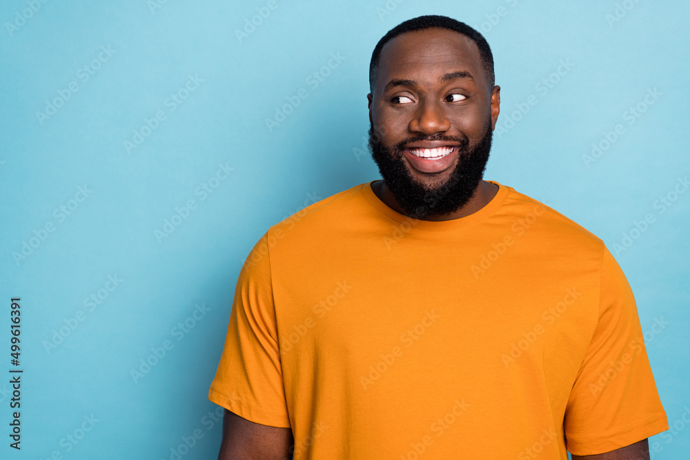 Photo of cheerful dreamy guy dressed orange t-shirt looking empty space smiling isolated blue color background Photo of cheerful dreamy guy dressed orange t-shirt looking empty space smiling isolated blue color background