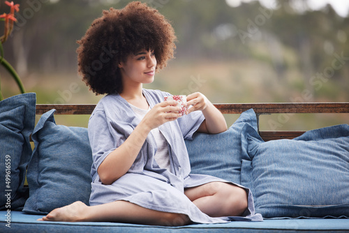 Beautiful view, theyll set it on fire for something new. Shot of an attractive young woman relaxing with a cup of coffee outside on the patio. photo