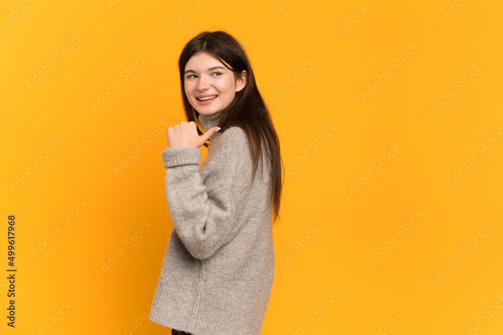 Young Ukrainian girl isolated on yellow background pointing to the side to present a product Young Ukrainian girl isolated on yellow background pointing to the side to present a product
