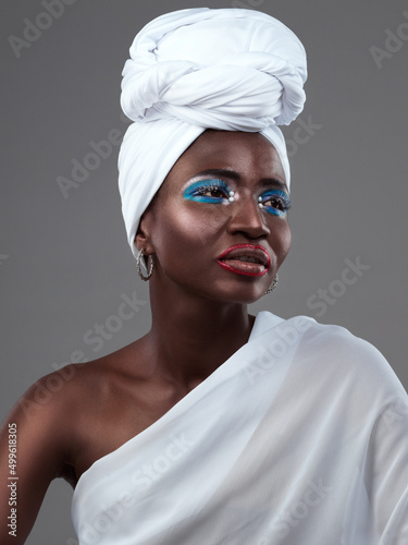So much style in one garment. Studio shot of an attractive young woman posing in traditional African attire against a grey background.