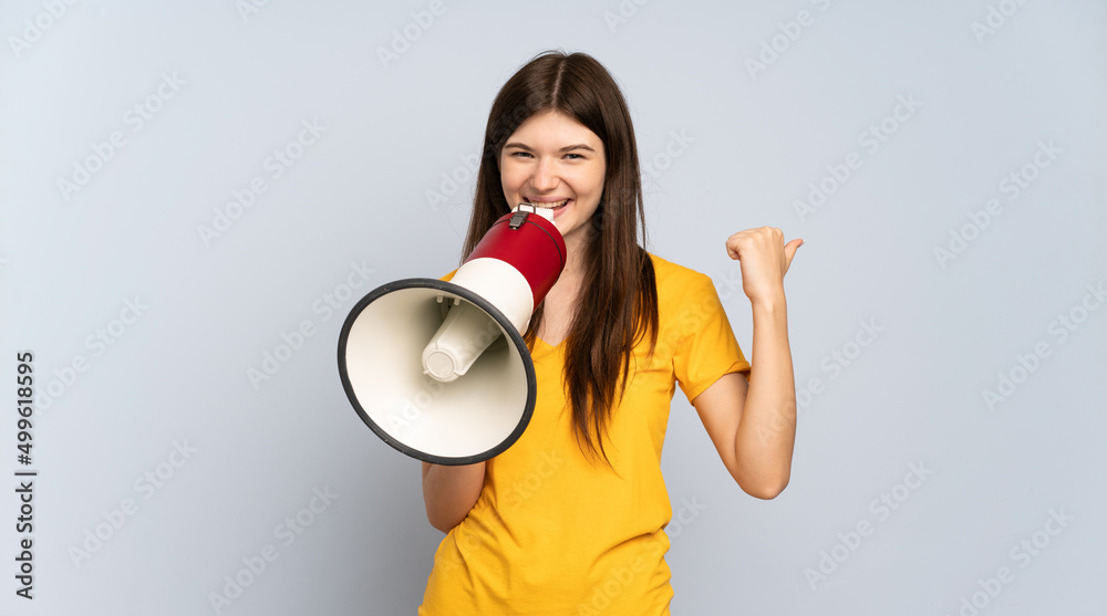 Young Ukrainian girl isolated on white background shouting through a megaphone and pointing side Young Ukrainian girl isolated on white background shouting through a megaphone and pointing side