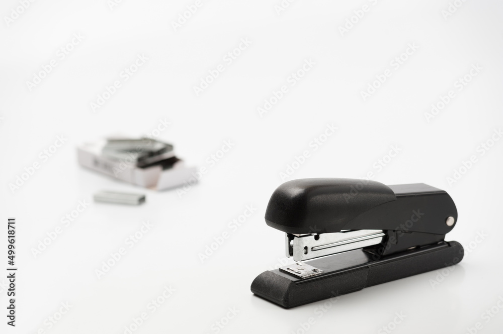 The black office stapler with paper clips container on the white background The black office stapler with paper clips container on the white background