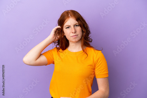 Teenager redhead girl over isolated purple background having doubts