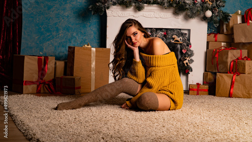 Smiling young woman opening a gift box near beautiful Christmas tree at home. Luxurious Christmas decoration. Presents for Christmas and New Year. © Oleksandr